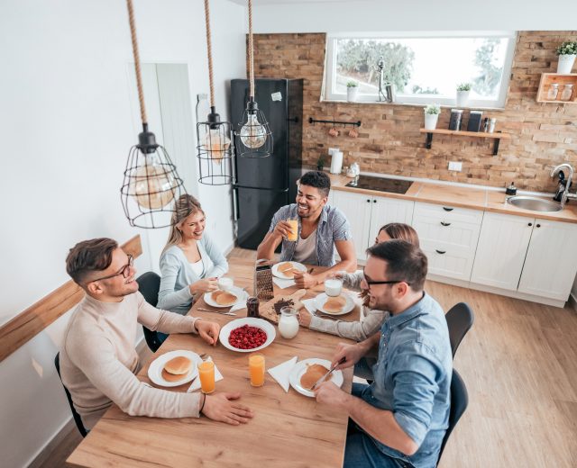 living in shared accommodation friends sitting at table eating pancakes